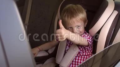 小快乐的男孩坐在一辆<strong>小汽车</strong>的座位上，竖起大拇指。